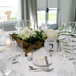 White-and-green reception centerpiece styled with driftwood and candlelight.