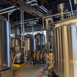 the inside of a brewery - Interior of a brewery featuring stainless steel fermentation tanks, pipes, and brewing equipment in a spacious, industrial setting.