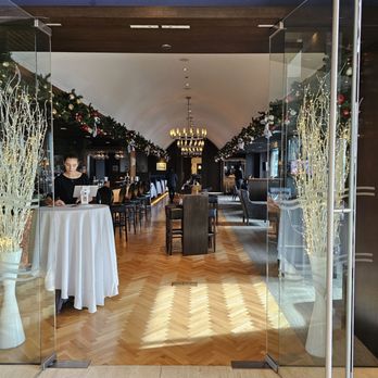 Zorba Lounge - A restaurant entrance decorated with holiday garlands and lights, leading into a dining area with tables, chairs, and a chandelier. - Lounges Near Me - Naperville, Illinois