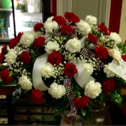 A Touch of Class Florist - Casket cover 1/2 size Crimson and white carnations, mixed greenery, baby's breath with white and Alabama ribbon embellishments.