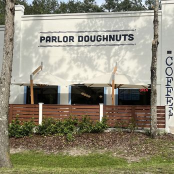 Parlor Doughnuts - Parlor Doughnuts' exterior features a white building with outdoor seating, umbrellas, and a wooden fence, with a visible 'OPEN' sign. - Coffee & Tea Near Me - Fruit Cove, Florida