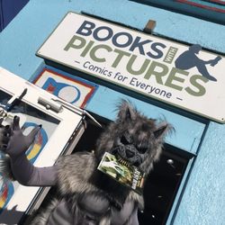 Books with Pictures - Werwolf standing in front of comic book store, books with pictures, holding a comic book in their mouth.