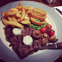 The Burnbrae - 10oz Black Angus ribeye with garlic herb butter, chips, rings, grilled cherry tomatoes, mushrooms  and peas