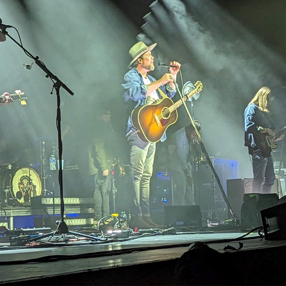 Kiva Auditorium - a man playing a guitar and singing into a microphone - Music Venues Near Me - Albuquerque, New Mexico