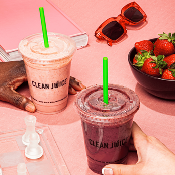 Clean Juice - a person holding a cup of clean juice next to a bowl of strawberries - Juice Bars & Smoothies Near Me - Davidson, North Carolina