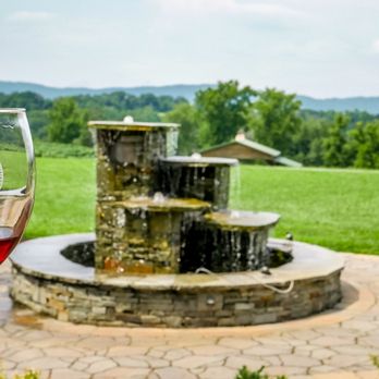 Spout Spring Estates Winery and Vineyard - a glass of wine in front of a fountain - Wineries Near Me - Blaine, Tennessee