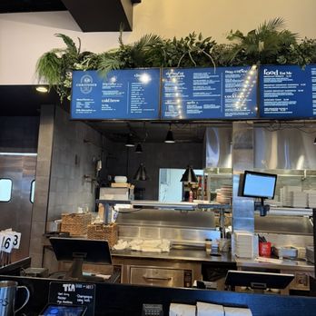 Revolve Hall - Menu of coffee shop - A coffee shop counter with digital menu boards above, showing various drink options, and a kitchen area with equipment behind. - Tacos Near Me - Apple Valley, Minnesota