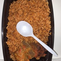 Comfort's African Cuisine - The jollof rice with 2 meats for $20 pre-tax. Small plastic spoon for size reference.