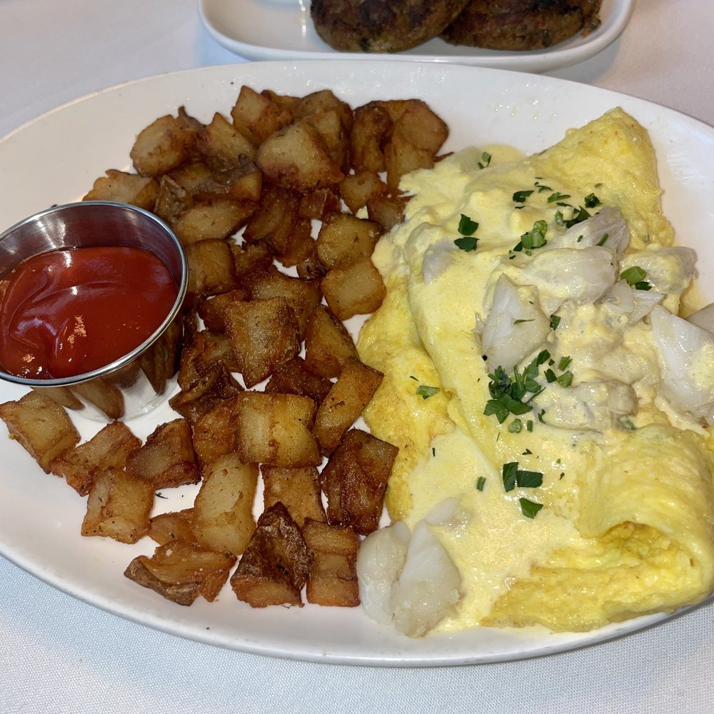 OMELETTE OSCAR: three-egg omelet, fines herbes, asparagus, crabmeat, hollandaise; served with Brabant potatoes