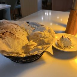 Fresh bread - A basket of naan bread and a scoop of ice cream with sprinkles are placed on a white table in a restaurant setting.