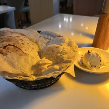 Selda - Fresh bread - A basket of naan bread and a scoop of ice cream with sprinkles are placed on a white table in a restaurant setting. - Mediterranean Near Me - Irving, Texas