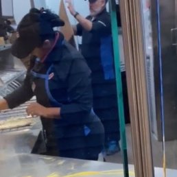 Staff preparing a pizza using her bare hands.