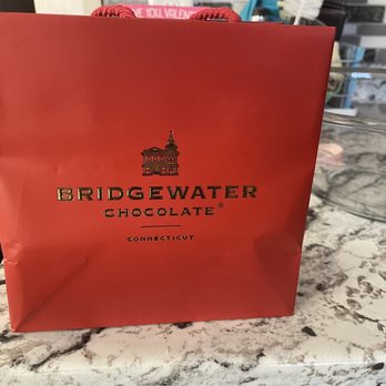 Bridgewater Chocolate - a red paper bag on a marble countertop - Chocolatiers & Shops Near Me - Brookfield, Connecticut
