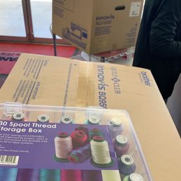 A sewing machine, embroidery machine and a set of thread all at the check out line.