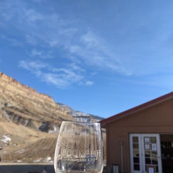 Bookcliff Vineyards - a hand holding a wine glass - Wine Tasting Room Near Me - Palisade, Colorado Bookcliff Vineyards - a hand holding a wine glass - Wine Tasting Room Near Me - Palisade, Colorado