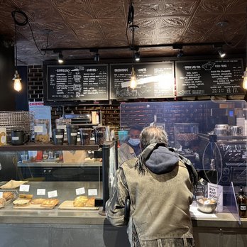 Ground Central Coffee - a man standing in front of a bakery counter - Coffee & Tea Near Me - New York, New York Ground Central Coffee - a man standing in front of a bakery counter - Coffee & Tea Near Me - New York, New York