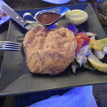 718 Bistro - A square black plate holds fried fish fillets, mixed vegetables, mashed potatoes, and a sauce in a small metal container, served at a restaurant. - Cafes Near Me - Brooklyn, New York