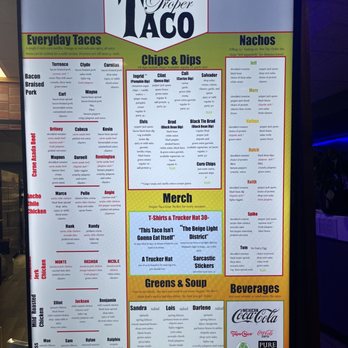 Proper Taco - Current Menu - The menu board at Proper Taco presents a variety of taco options, chips, dips, and beverages. It includes sections for everyday tacos, nachos, chips & dips, and a merchandise area. The menu lists specific taco fillings, sides, and drink choices, with some items marked as vegan. The board is organized with headings, descriptions, and prices, and features a section for beverages with logos of drink brands. The background is primarily green, white, and yellow, with red accents. - Tacos Near Me - Midland, Michigan