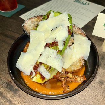 Pretty Penny - Salad - A salad featuring cheese shavings, greens, toasted bread, and a sauce, served in a black bowl on a wooden table. - Cocktail Bars Near Me - Phoenix, Arizona