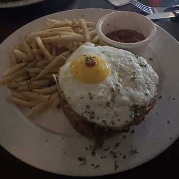 ALC Steaks - Red eye - A meal featuring French fries, a fried egg on top of a piece of bread or meat, and a small bowl of ketchup, served on a white plate. - Steakhouses Near Me - Austin, Texas