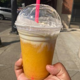 a hand holding a cup of orange juice a hand holding a cup of orange juice