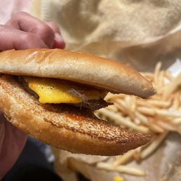 a person holding a sandwich with cheese and egg