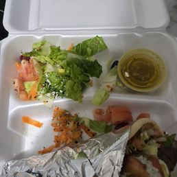 A gyro sandwich, some dressing and a couple pieces of lettuce.