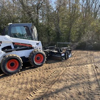 Bluegrass Landscapes - a bobcat ski - loader on a dirt road - Snow Removal Near Me - Lexington, Kentucky