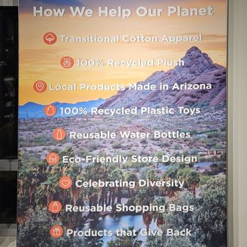 Zoolights - A tall, vertical sign displays Phoenix Zoo's eco-friendly efforts, including recycled materials and local products, against a desert mountain landscape background. - Zoos Near Me - Phoenix, Arizona