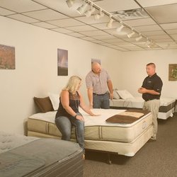 Millersburg Electric - A retail showroom featuring several mattresses on display. A sales associate is assisting a couple who are testing the comfor...