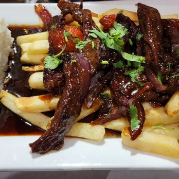 Bandeja Paisa - Lomo Salteado: steak and onions with cherry tomatoes with ponzu sauce over fries served with rice. - Colombian Near Me - Orlando, Florida