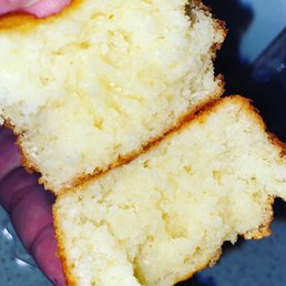 Two slices of yellow cake with a crumbly texture and golden-brown edges are shown, held in a person's hand.