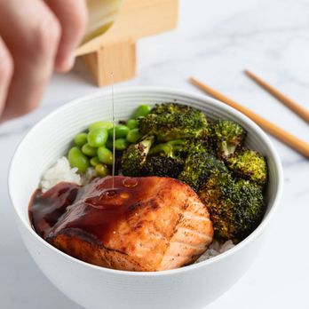 Belly Fish - a person pouring sauce over a bowl of broccoli - Sushi Bars Near Me - Miami, Florida