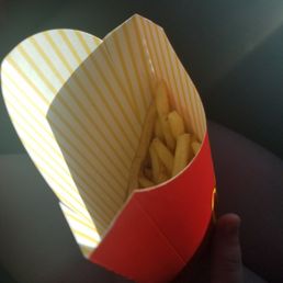 a hand holding a box of french fries a hand holding a box of french fries