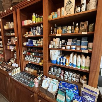 Boston General Store - Wooden retail shelves display skincare, cosmetics, and personal care items, including creams, serums, and soaps, in a store setting. - Accessories Near Me - Brookline, Massachusetts