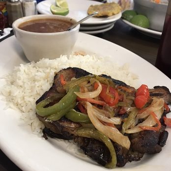 El Banquete - Chuleta encebollada, tostón al fondo (grilled pork chop with peppers, onions, rice, and beans; in the background a fried plantain) - Salvadoran Near Me - Suffern, New York El Banquete - Chuleta encebollada, tostón al fondo (grilled pork chop with peppers, onions, rice, and beans; in the background a fried plantain) - Salvadoran Near Me - Suffern, New York