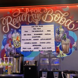 A menu board displaying various bubble tea flavors and toppings, with colorful illustrations of drinks and toppings on a wall.
