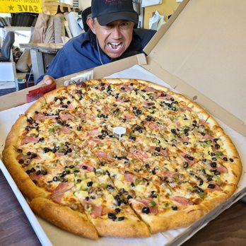Brick Shack Pizza - a smiling man holding a large pizza - Pizza Near Me - Ontario, California Brick Shack Pizza - a smiling man holding a large pizza - Pizza Near Me - Ontario, California