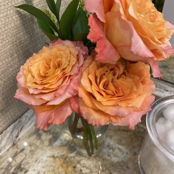 Life Time - Such a nice touch - A floral arrangement of peach and pink roses with green leaves in a glass vase, placed on a marble countertop. - Gyms Near Me - Austin, Texas