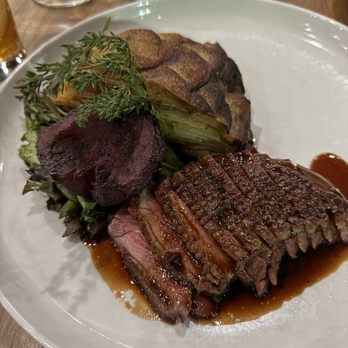 Feast - Duck - A dish featuring sliced beef with a brown sauce, accompanied by roasted vegetables and garnishes, served on a white plate. - New American Near Me - Gibsonia, Pennsylvania