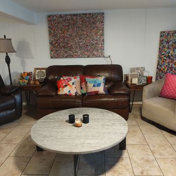 Ultimate Treasures - A living room features three armchairs, a coffee table, and colorful abstract artwork on the walls, with a window on the left. - Antiques Near Me - Downers Grove, Illinois