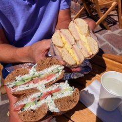 Bubbe's Fine Bagels - Rye Bagel w/ Chive & Green Onion Schmear, cucumber, and tomato (front) + Everything Bagel w/ Egg & Cheese w/ ham (back)