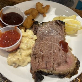 Robert's Buffet - A plate features a large cooked steak with ketchup, macaroni and cheese, lemon wedges, and fried shrimp with dipping sauces. - Buffets Near Me - Riverside, Iowa