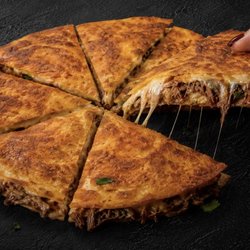 A close up of our 13" pie filled with mozzarella cheese and our famous birria with onion and cilantro! Served with (2) 8oz consommé