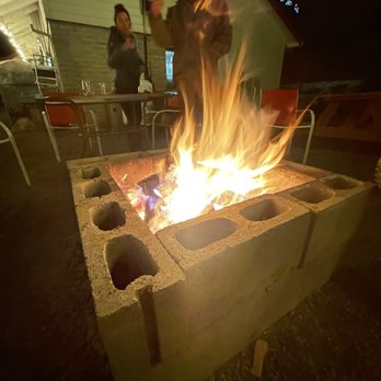 Applegate Country Club - a woman standing over a fire pit - Pizza Near Me - Applegate, Oregon
