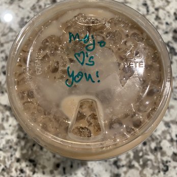 Mojo Coffee - Cute message! They know little things matter! - A clear plastic cup contains a cold drink with ice cubes, likely iced coffee or tea. The cup's lid has a handwritten message in blue ink that reads 'You ♥ me!'. The background is a speckled granite countertop, and the image is taken from above, focusing on the drink and message. - Coffee & Tea Near Me - Round Rock, Texas