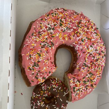 Donutopolis - Birthday donut with a slice cut out and a regular sized donut to show you how HUGE this donut is - Donuts Near Me - Poway, California