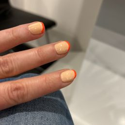 Regular French manicure with pale peach base color and neon orange tips.