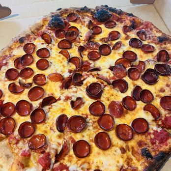 Prisco's - A rectangular pepperoni pizza with melted cheese and evenly distributed pepperoni slices is shown in an open cardboard pizza box. The crust has some charred areas, indicating it was baked at high temperature. The pizza appears freshly cooked, with a golden-brown crust and a layer of melted cheese covering the toppings. - Delis Near Me - Bridgewater, Massachusetts