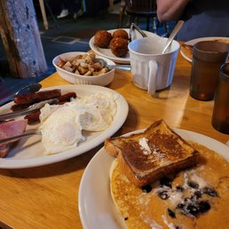a breakfast of pancakes, eggs, bacon, and blueberries